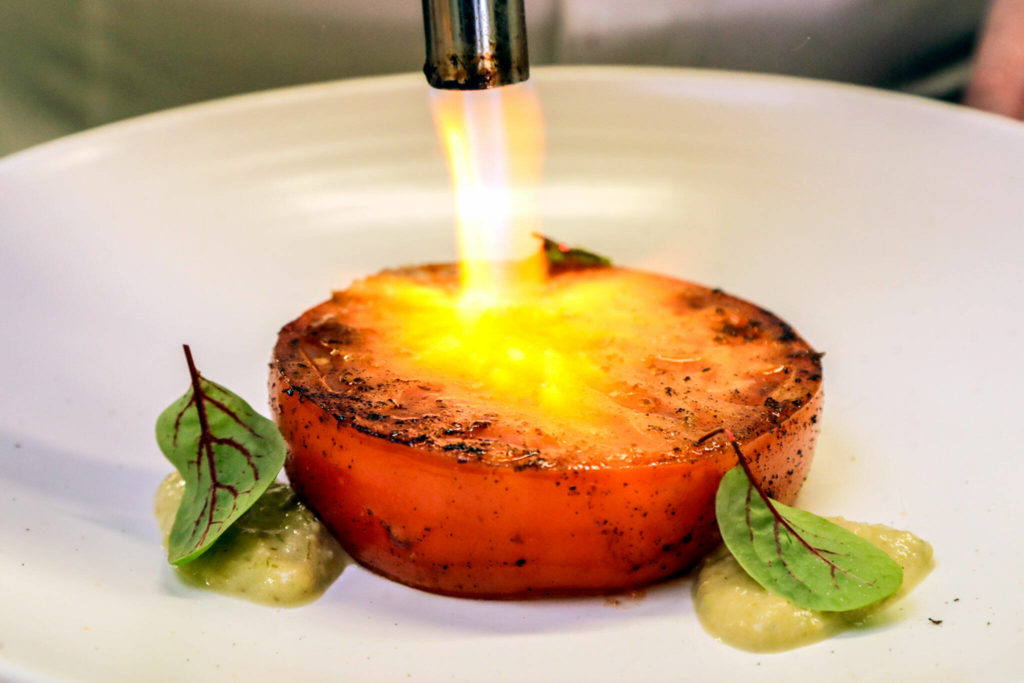 Joel Childs uses a kitchen torch to char a tomato at The Chef Behind The Curtain in Snohomish. (Kevin Clark / The Herald)
