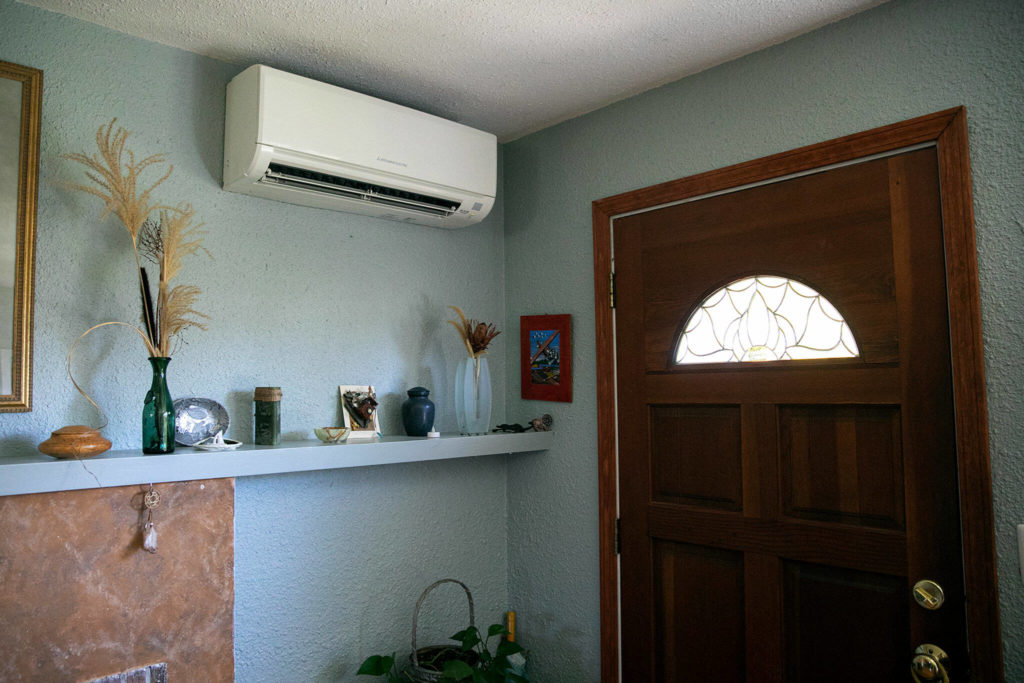 A combination cooler and heater, top center, hangs on the wall in Julie Martinson’s home Wednesday, in Everett. (Ryan Berry / The Herald) 
