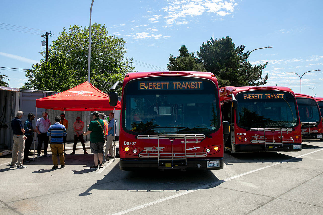 Officials gather outside two of Everett’s electric buses to discuss the new BattGenie system on Monday, June 27, 2022, at the Everett Transit bus yard in Everett, Washington. (Ryan Berry / The Herald)