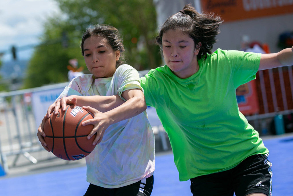 Two players chase down the ball while playing at “Center Court” Saturday during Everett 3on3 in downtown Everett. (Ryan Berry / The Herald)
