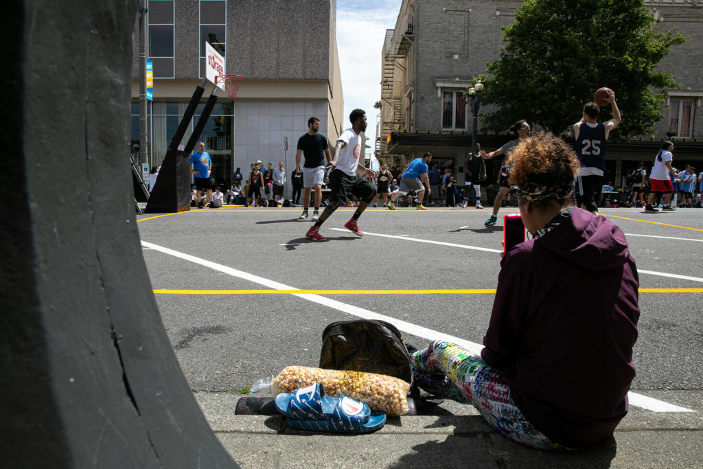 A woman records a game Saturday during the Everett 3-on-3 basketball tournament in downtown Everett. (Ryan Berry / The Herald)
