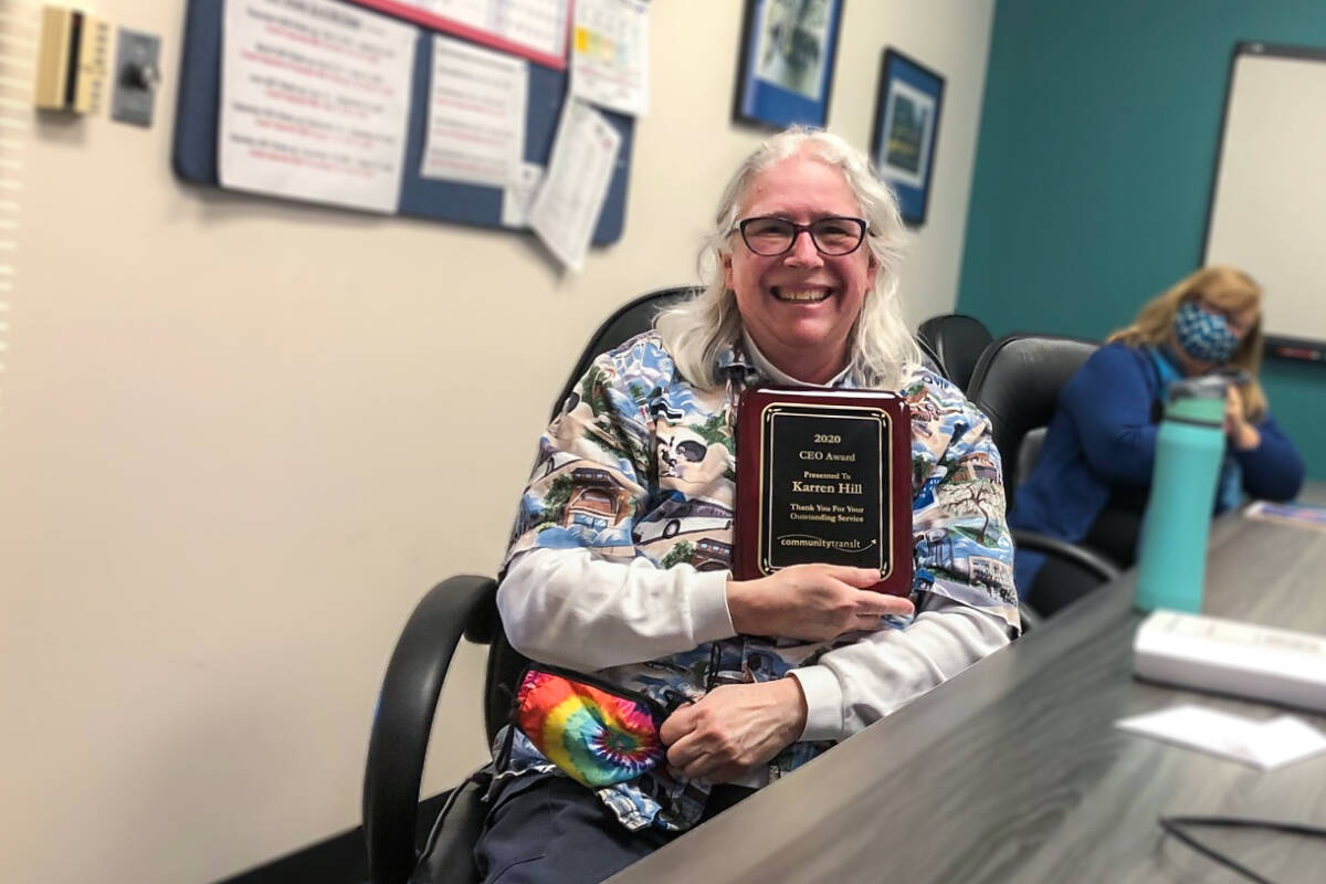 Karren Hill, who has served as a bus driver with Community Transit for over 40 years, smiles with an Employee Excellence Award that she was given.