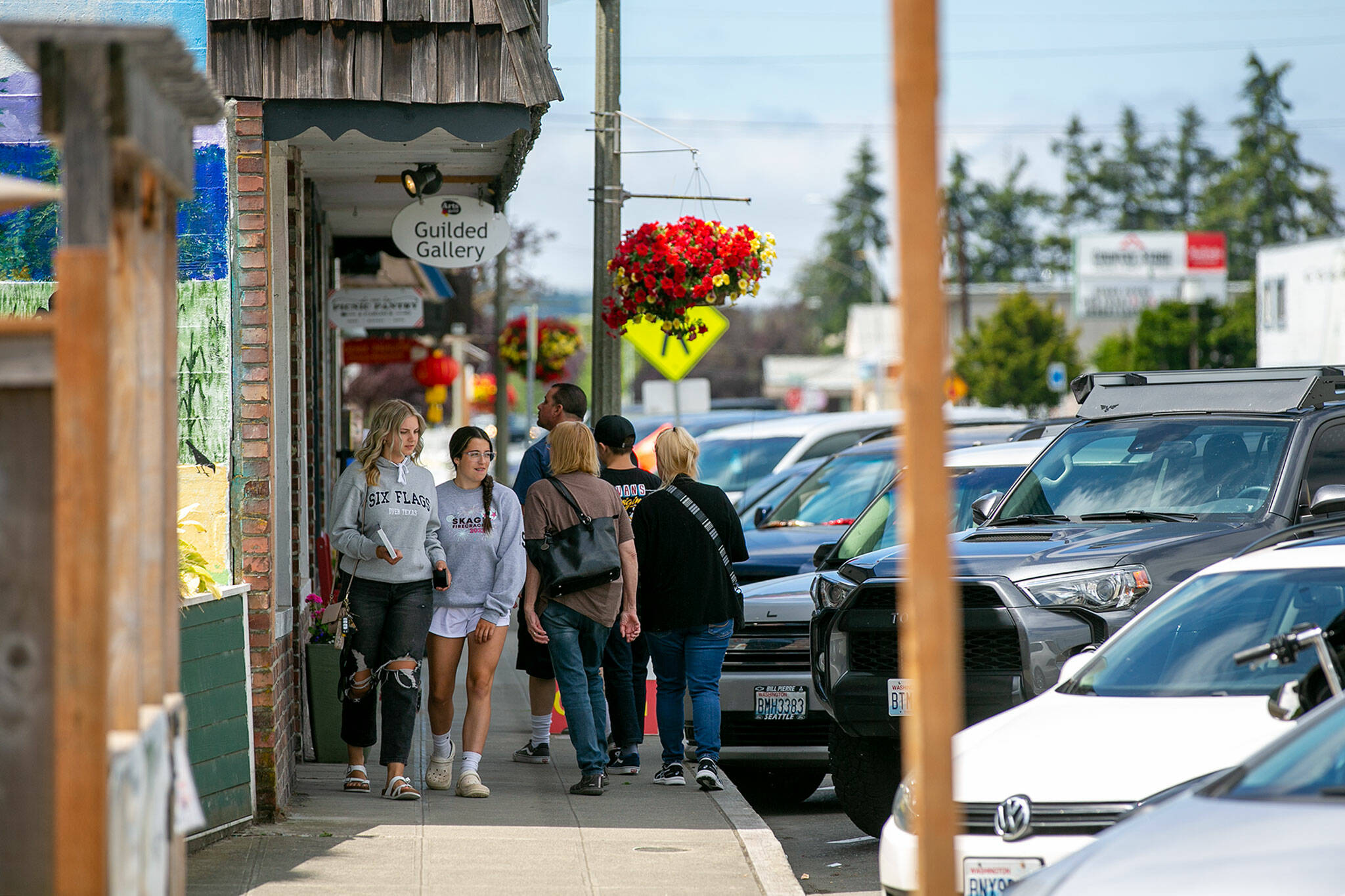 Two groups of pedestrians sneak past each other on a narrow sidewalk along 271st Street on Friday, in the Historic East Downtown in Stanwood. (Ryan Berry / The Herald)