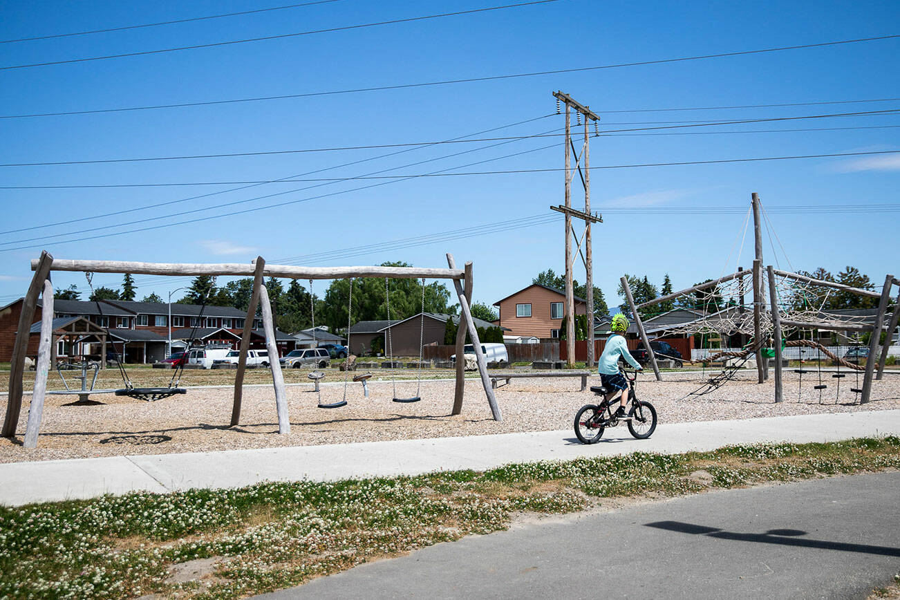 A child rides their bike past the Frontier Heights Park playground on Friday, July 15, 2022 in Lake Stevens, Washington. (Olivia Vanni / The Herald)