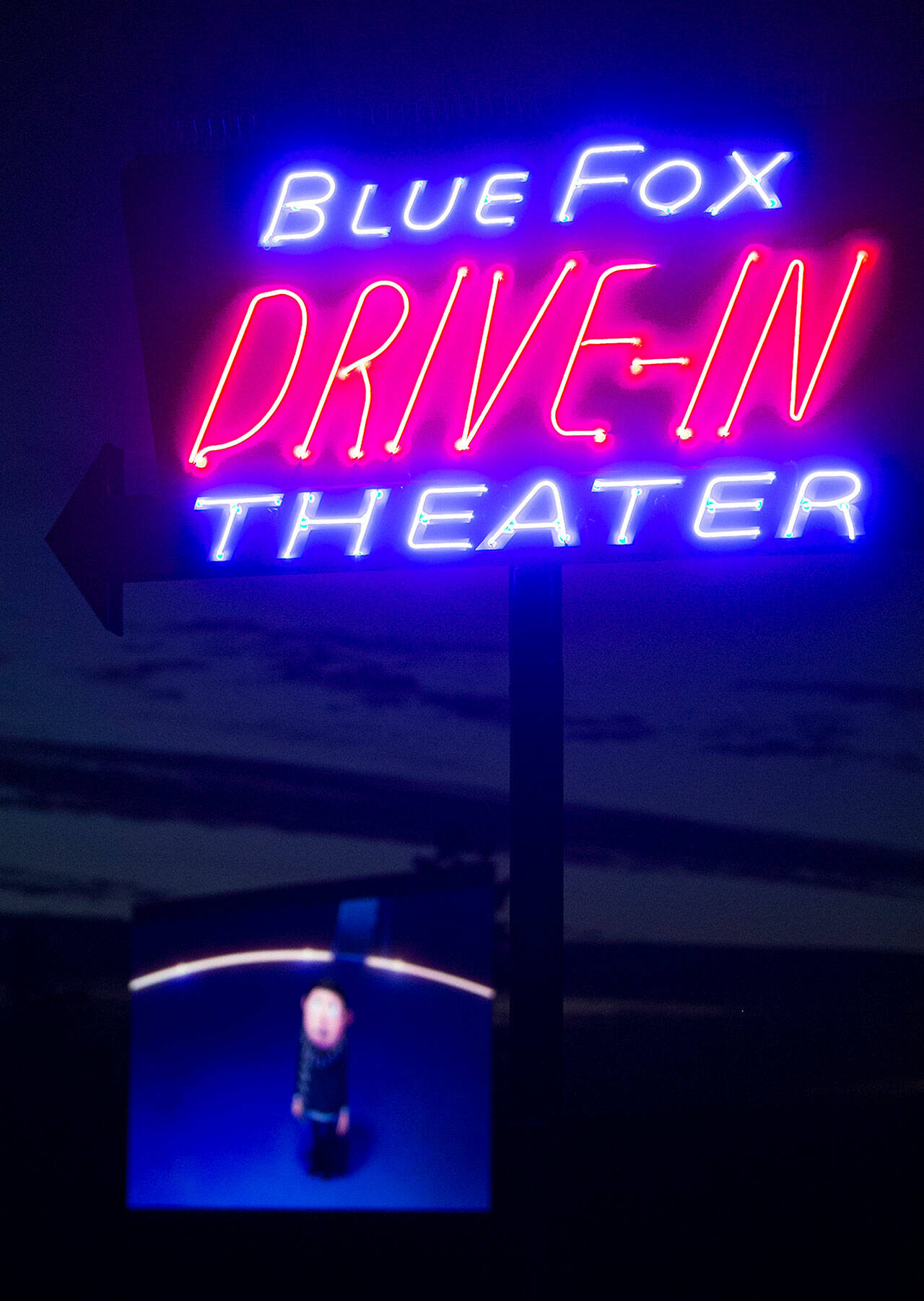 “Minions: The Rise of Gru” plays on the projector screen as the Blue Fox Drive-In Theater sign glows in the nighttime at the Oak Harbor outdoor movie theater. (Ryan Berry / The Herald)