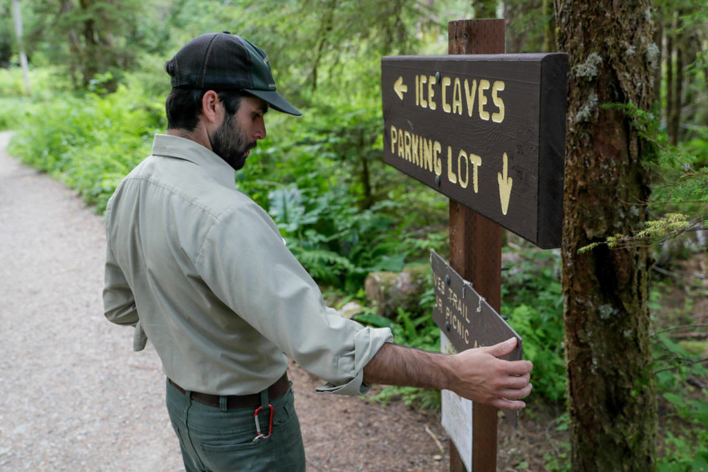 Justin Sundstrom, Forest Service ranger, examines a partially completed sign on the Ice Cave trail on July 23 near Granite Falls. (Kevin Clark / The Herald)

