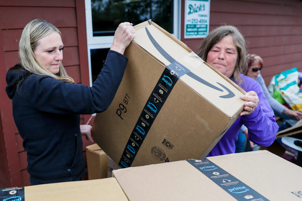 Leslie Wall, left, and Kim Mantyla stack donated dog food Monday afternoon at the Everett Animal Shelter. Donations poured in after the shelter posted a plea to Facebook last week. (Kevin Clark / The Herald)
