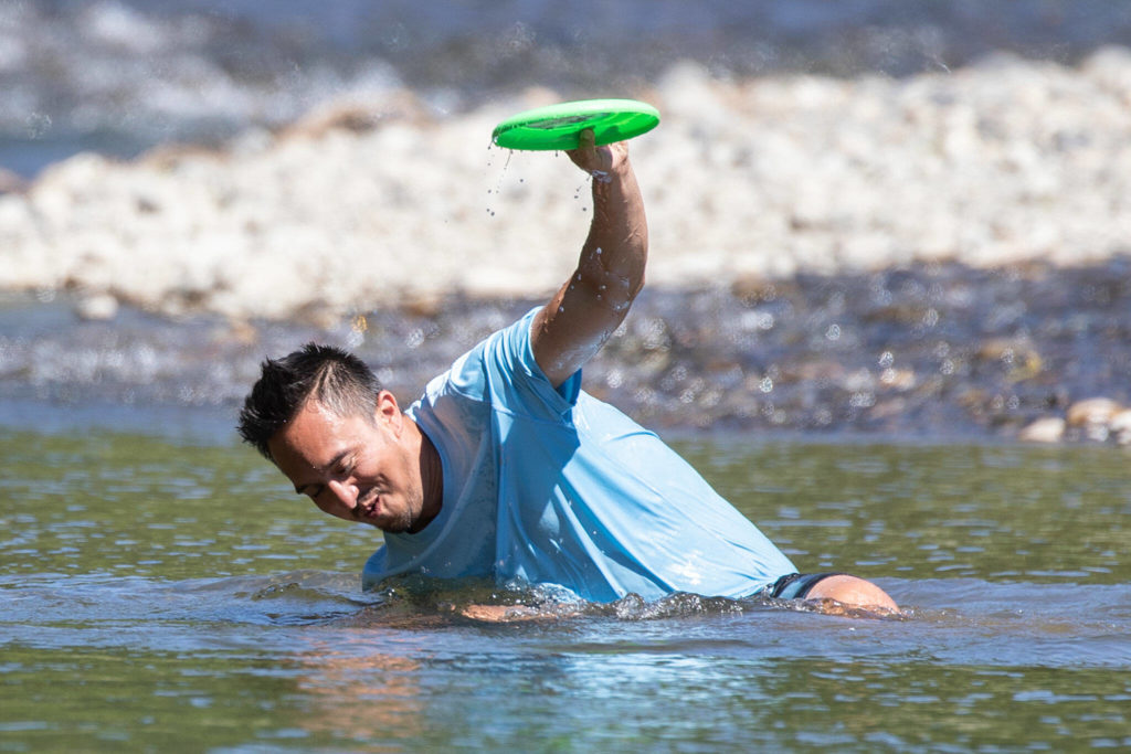 Justin Ofrancia gathers himself catching a frisbee Wednesday afternoon in the waters of the Pilchuck River in Snohomish. (Kevin Clark / The Herald)
