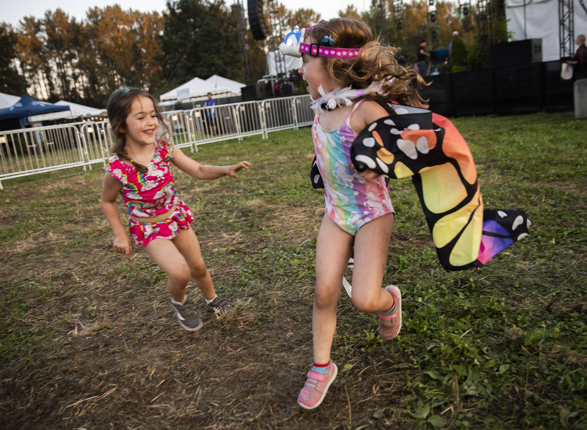 Coral Roussell, 4, left, chases Penelope Witter, 5, around the grass in front of the Garden Stage on Thursday, in Snohomish. (Olivia Vanni / The Herald)