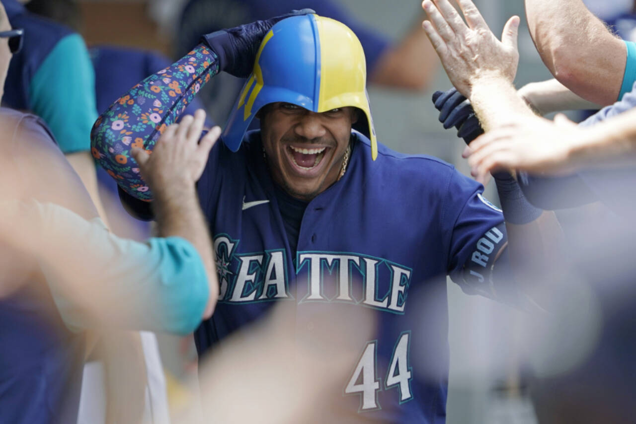 Seattle Mariners’ Julio Rodriguez wears a helmet as he is greeted in the dugout after his three-run home run against the Texas Rangers during the seventh inning of a Wednesday’s game in Seattle. (AP Photo/Ted S. Warren)