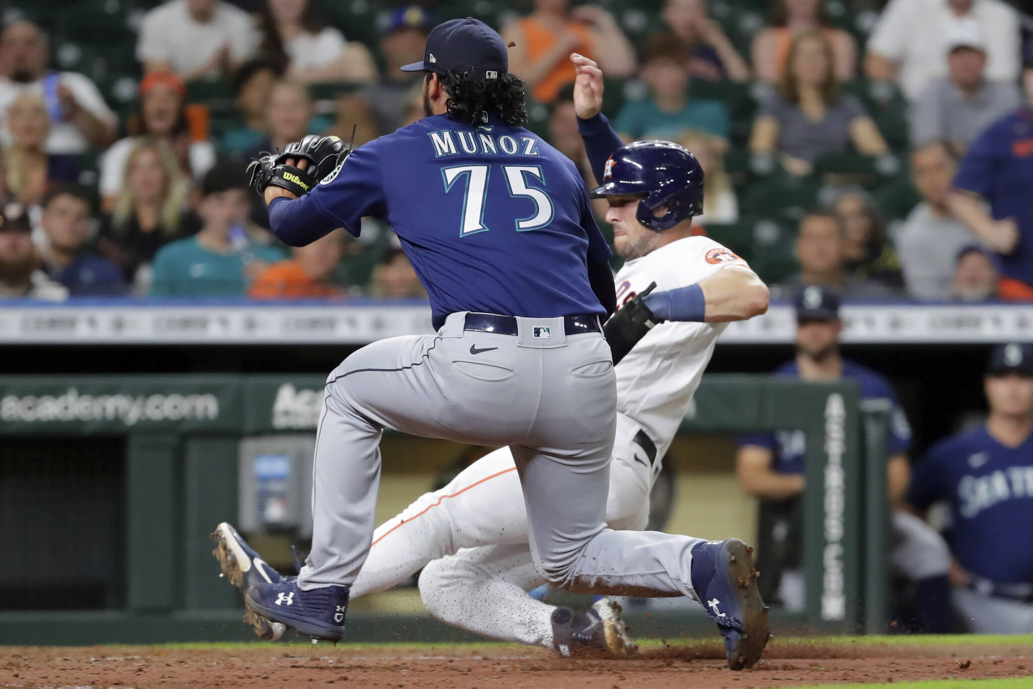 Mariners relief pitcher Andres Munoz (75) runs to home plate after his wild pitch, while the Astros’ Alex Bregman slides to score during the eighth inning of a game Thursday in Houston. (AP Photo/Michael Wyke)