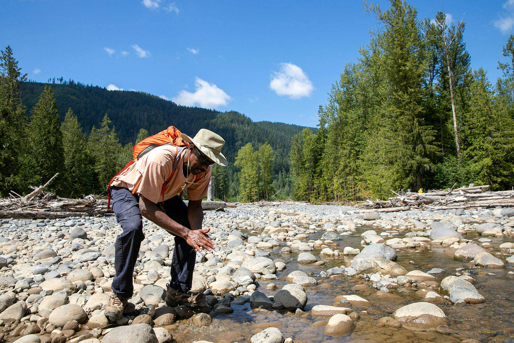 Don Smith, a Community Transit bus driver who has held an interest in rocks, minerals and crystals for years, washes off a stone he is interested in bringing home on July 23 along the Nooksack River near Deming. (Ryan Berry / The Herald)