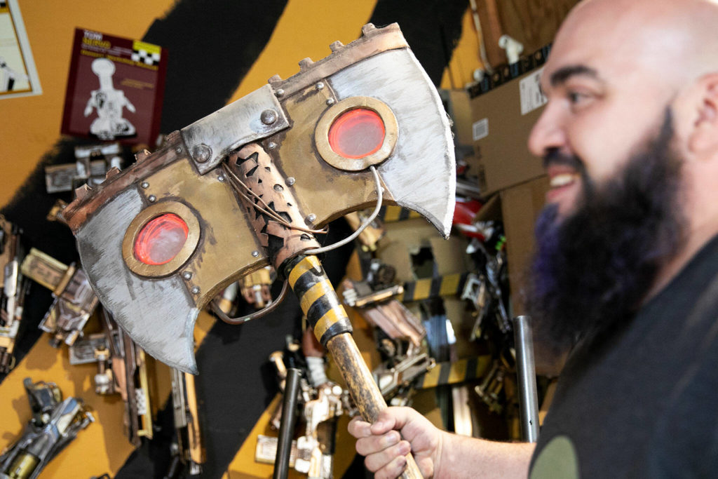 Josh Haazard holds an ax he made. Many of the devices he creates involve spinning or light-up features. (Ryan Berry / The Herald)
