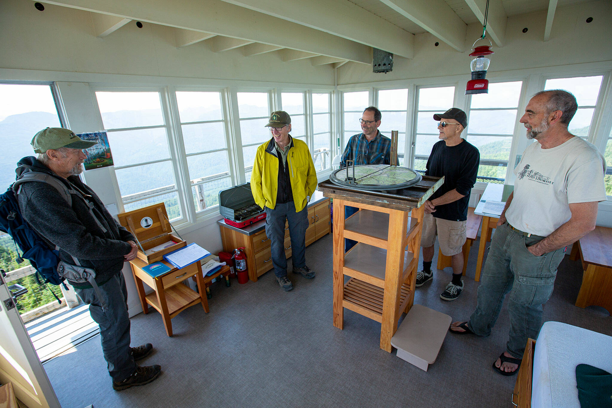 A group of visitors, many of whom were involved in the restoration of the lookout, spend time inside talking together on Wednesday, Aug. 10, at the North Mountain Fire Lookout north of Darrington. (Ryan Berry / The Herald)