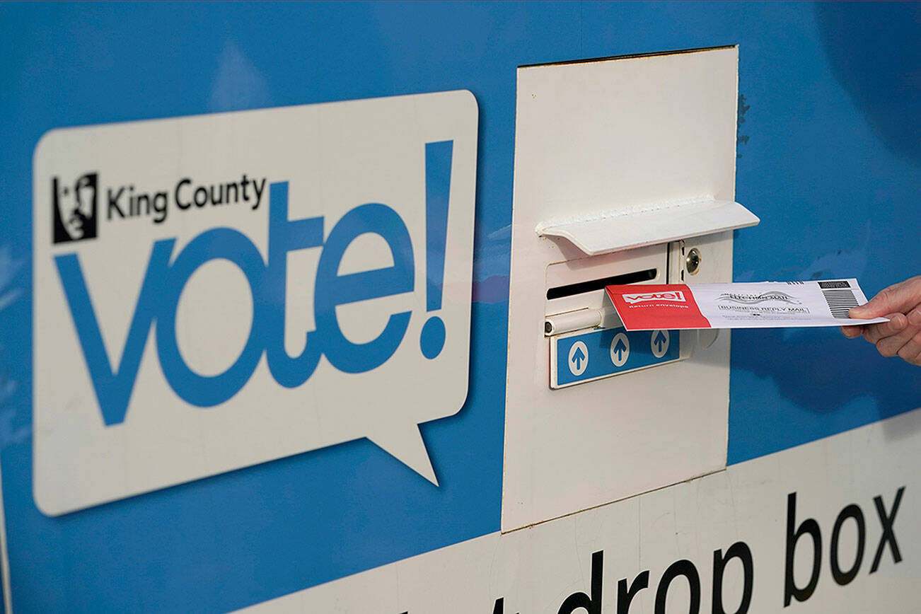 FILE - A person puts their ballot in a drop box on Oct. 27, 2020, at a library in Seattle. Washington state voters will winnow the field of candidates in dozens of races in the state's primary on Tuesday, Aug. 2, 2022. Washington is a vote-by-mail state, and voters must have their ballots postmarked and in the mail by Tuesday, or they can drop them off at drop boxes by 8 p.m. Under the state's primary system, the top two vote getters advance to the general election in November, regardless of party. (AP Photo/Ted S. Warren, File)