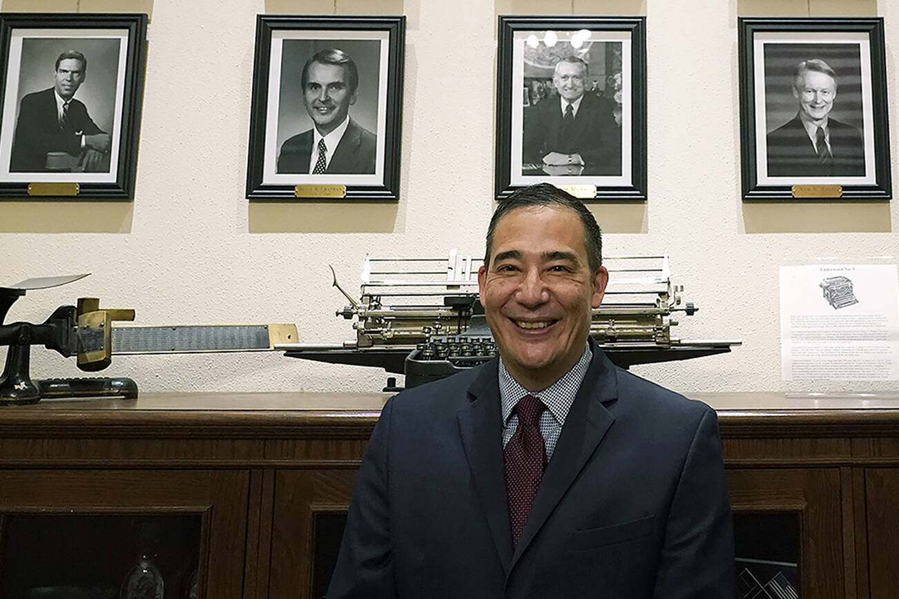 Steve Hobbs, who was sworn in as Washington Secretary of State, Monday, Nov. 22, 2021, at the Capitol in Olympia, Wash., poses in front of photos of the 15 people who previously held his office. Hobbs, a former state senator from Lake Stevens, Wash., is the first person of color to head the office and the first Democrat to serve as Secretary in more than 50 years. He replaces Republican Secretary of State Kim Wyman, who resigned to accept an election security job in the Biden administration. (AP Photo/Ted S. Warren)