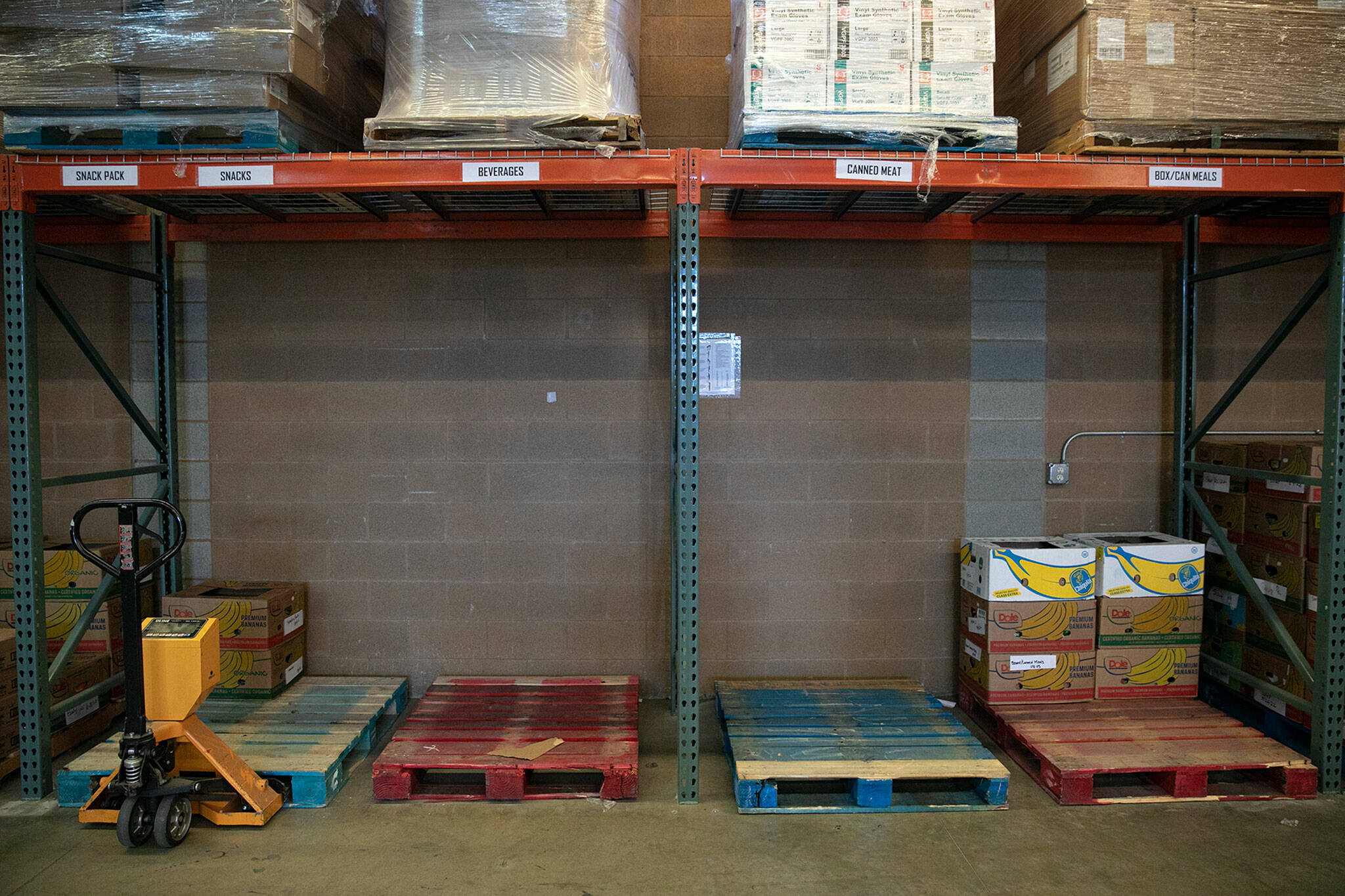 Pallets typically filled with foodstuffs are completely empty as the Everett Food Bank experiences never-before-seen shortages on Friday, in Everett. These storage areas are often two pallets deep, but many are now completely empty. (Ryan Berry / The Herald)