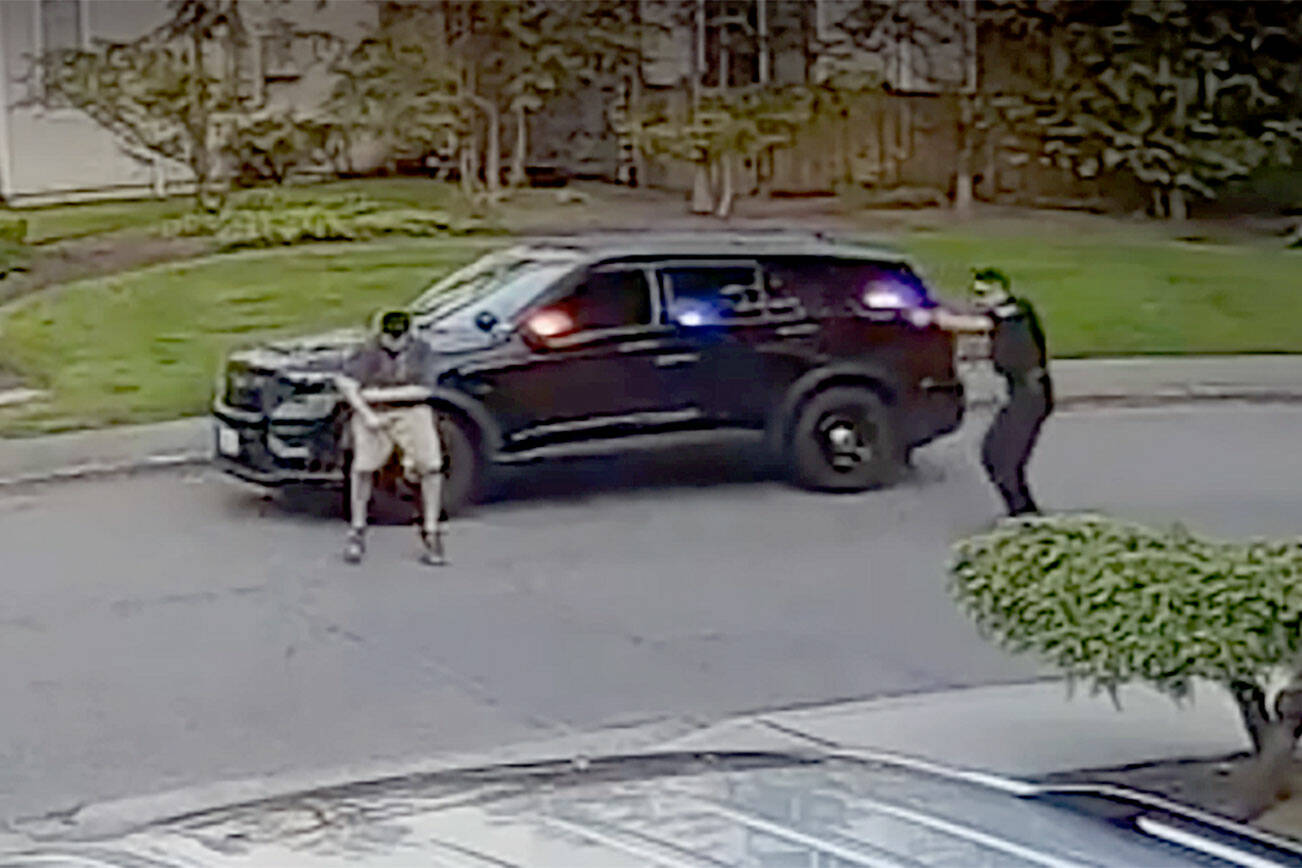 A frame from video taken by a nearby security camera shows a Bothell police officer (right) shooting a man who allegedly charged him with a knife. (Snohomish County Multiple Agency Response Team) 20210128