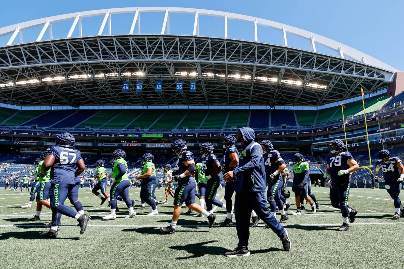 Seattle Seahawks offensive and defensive linemen jog up the field before the team's mock NFL football game Saturday, Aug. 6, 2022, in Seattle. (Jennifer Buchanan/The Seattle Times via AP)
