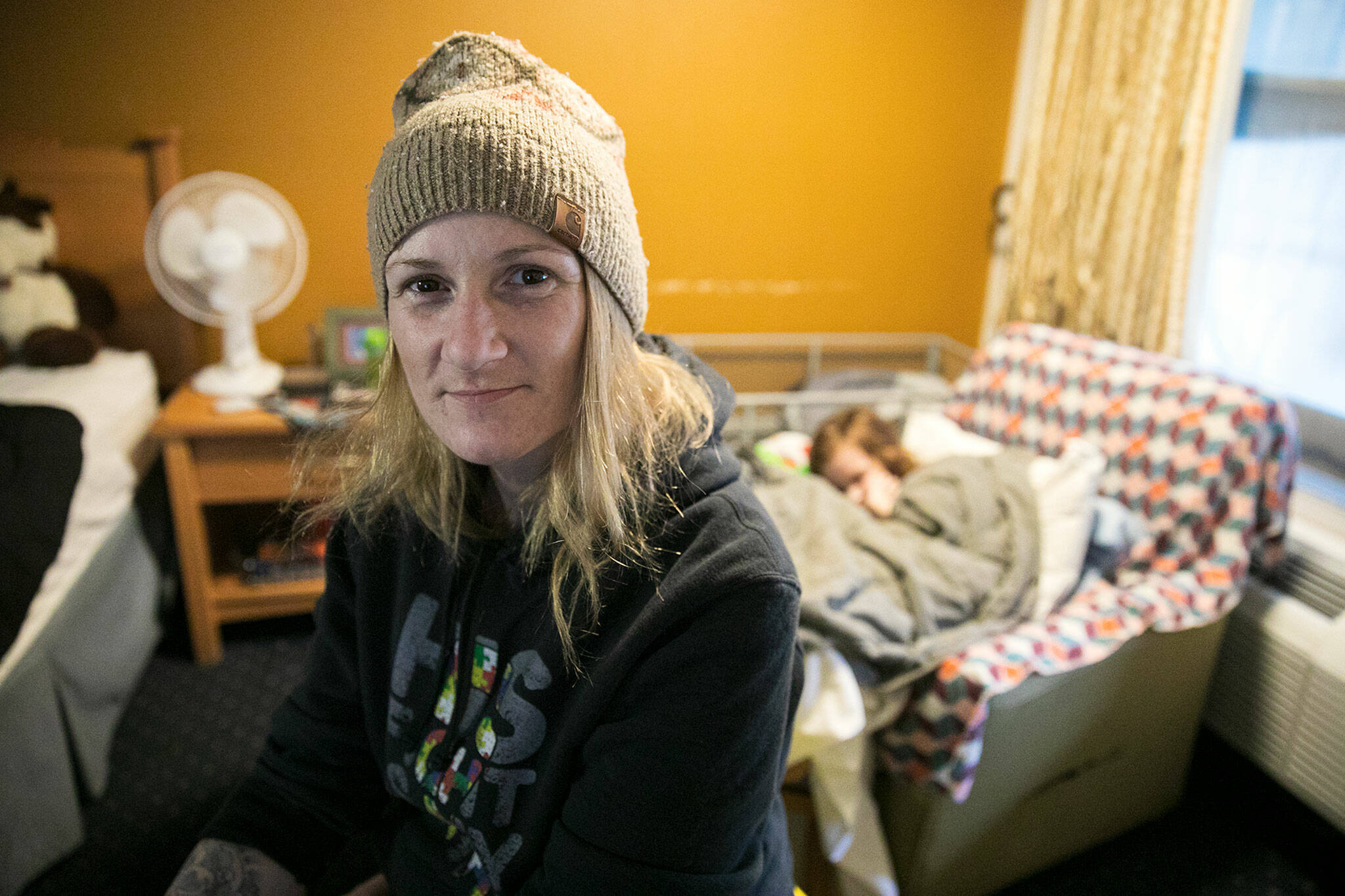 Melinda Parke sits inside a Days Inn motel room as her son, Elijah, sleeps on his chair behind her in April, in Everett. Used recently to house homeless indivudals and families with emergency vouchers, the hotel is proposed for purchase by the county for use as emergency supportive housing. (Ryan Berry / The Herald file photo)