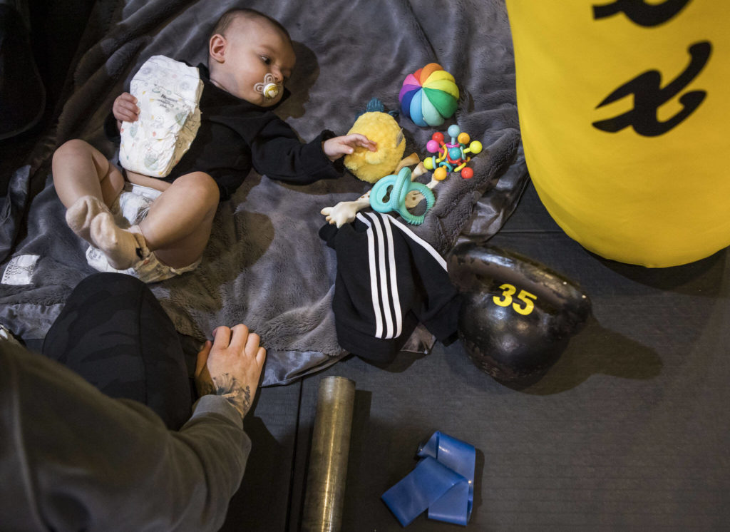 Austin holds onto a diaper and reaches for one of her toys while Miranda Granger gets ready to change her diaper at Charlie’s Combat Club on Monday, Feb. 28, 2022, in Everett, Washington. (Olivia Vanni / The Herald)
