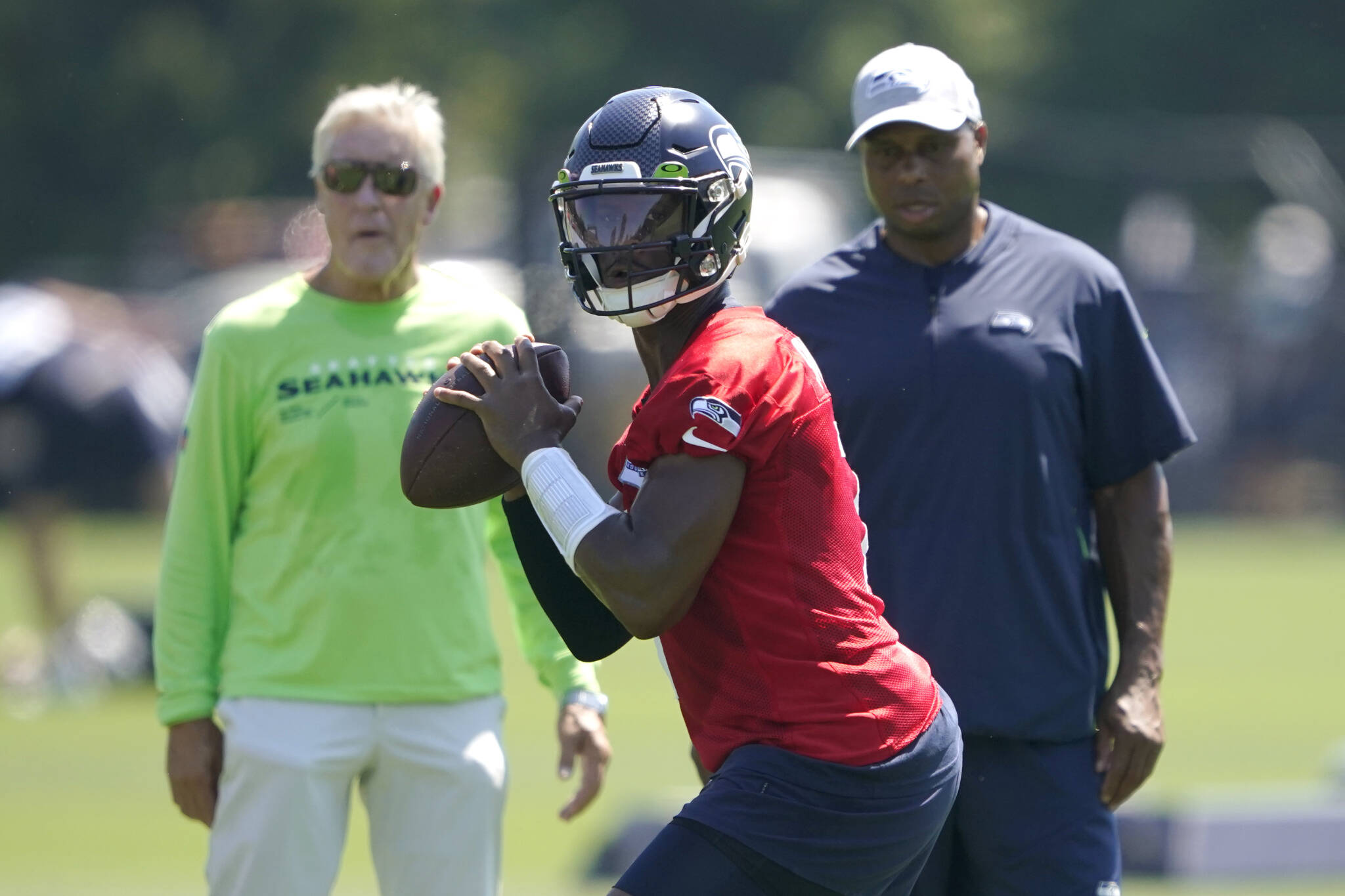 Seahawks quarterback Geno Smith (center) passes as head coach Pete Carroll (left) and assistant quarterbacks coach Kerry Joseph look on during a practice on July 30 in Renton. (AP Photo/Ted S. Warren)