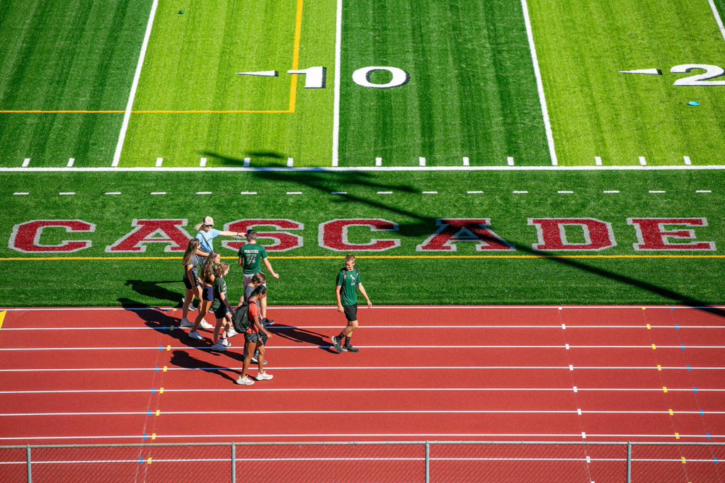 A group of student-athletes walk along the new track past Cascade High School’s name on Monday at Everett Memorial Stadium in Everett. (Ryan Berry / The Herald)
