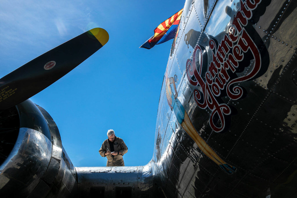 Crew Chief Dennis Fennessey stands on the wing of Sentimental Journey, a Boeing B-17 Flying Fortress, after a morning flight on Monday, at Arlington Municipal Airport in Arlington. (Ryan Berry / The Herald)
