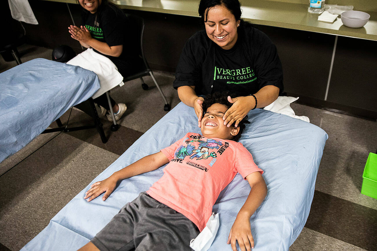 Zion Wright, 6, makes a face as Cecilia Guidarrama starts to massage cold facial cleanser onto his face during Evergreen Beauty College’s annual back-to-school beauty event on Wednesday, Aug. 17, 2022 in Everett, Washington. (Olivia Vanni / The Herald)