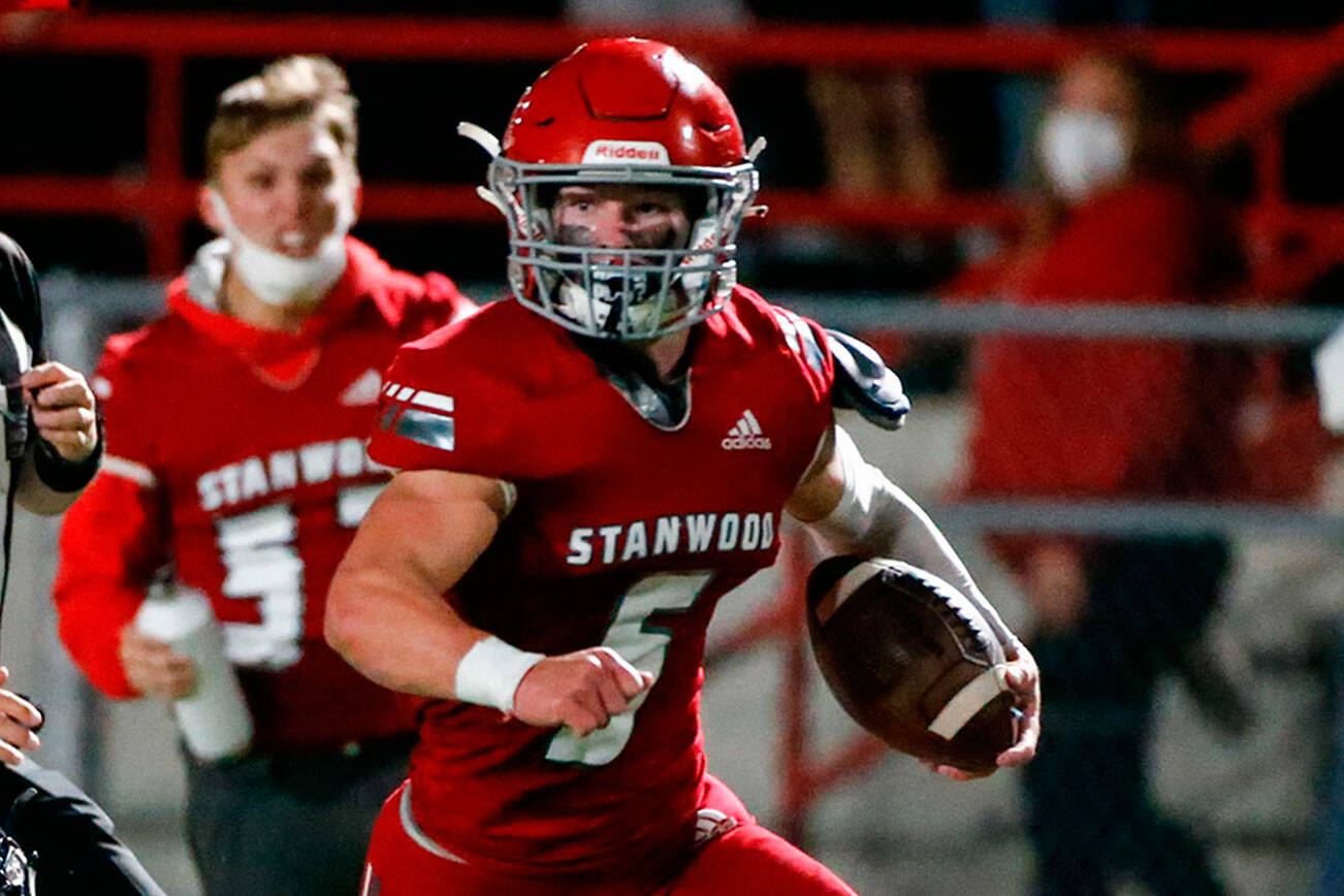 Stanwood's Ryder Bumgarner rushes with yardage with Arlington's Trenton Lamie, left, closing in the third quarter Friday night at Stanwood High School on September 24, 2021.  (Kevin Clark / The Herald)