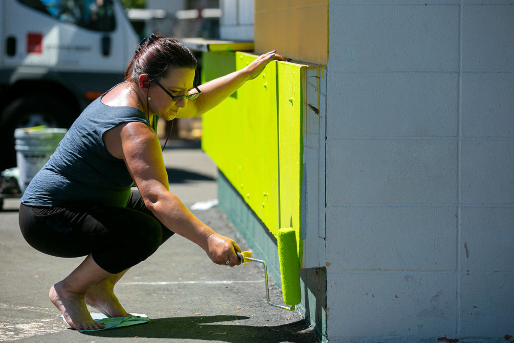 Darla Stoneking, who works at Evergreen Speedway, puts a fresh coat of paint on the Foodzilla food stand on Monday, at the Evergreen State Fairgrounds in Monroe. (Ryan Berry / The Herald)
