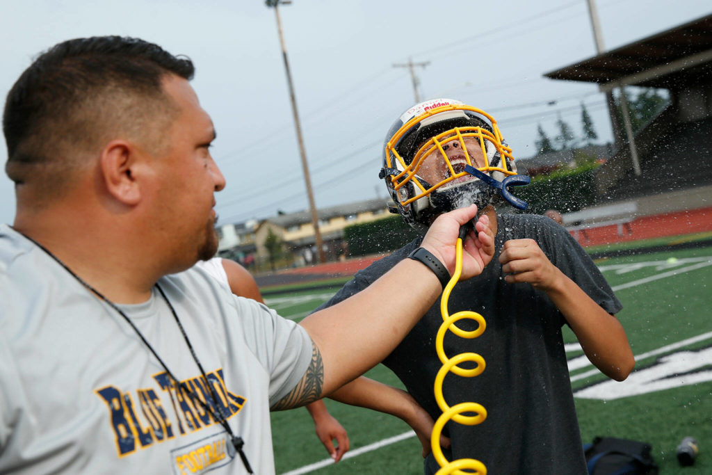 First year Mariner football head coach Tyler Tuiasosopo takes on water duty during his team’s practice Thursday, Aug. 18, 2022, at Mariner High School in Everett, Washington. (Ryan Berry / The Herald)
