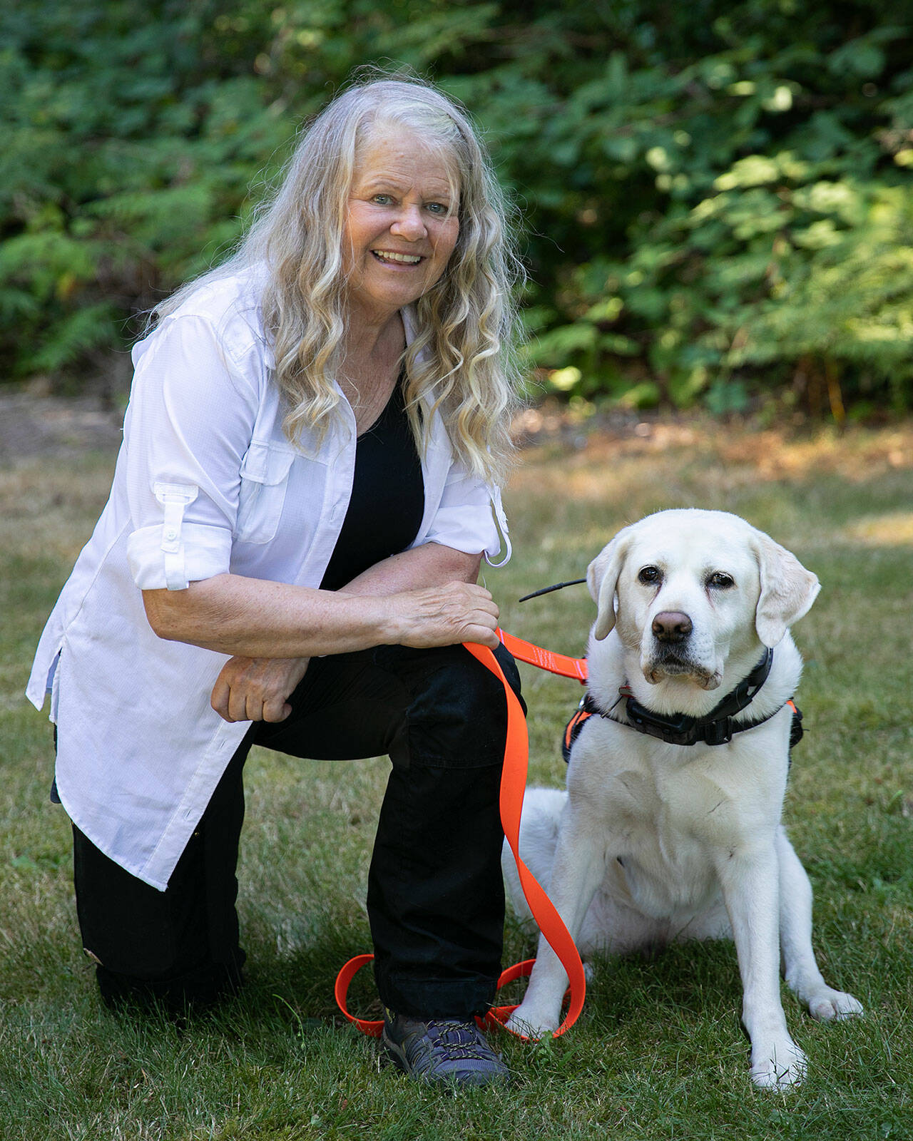 Suzanne Elshult takes a knee with her search-and-rescue dog, Keb, on Wednesday, Aug. 17, 2022, at Meadowdale High School in Lynnwood. (Ryan Berry / The Herald)