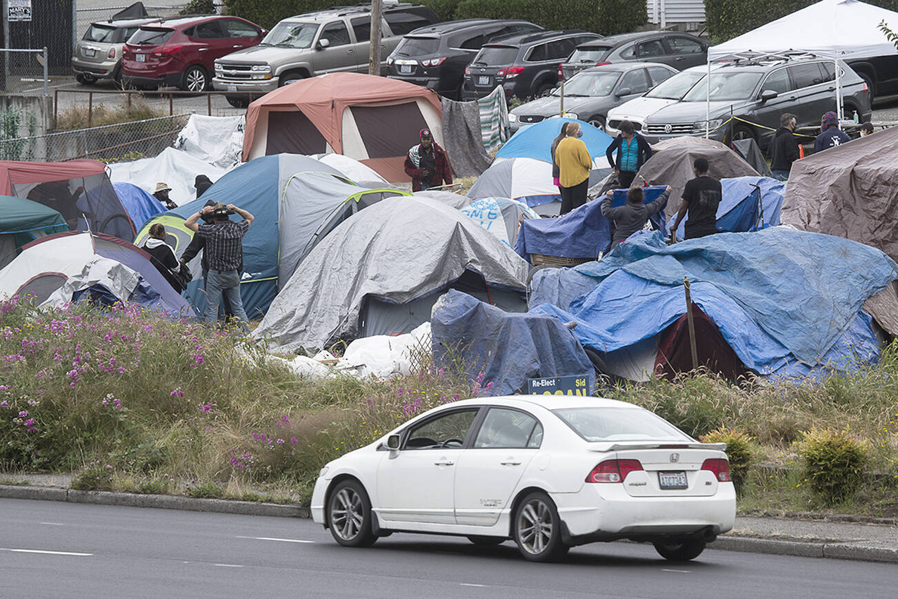 Cars drive by a homeless encampment at 3217 Rucker Avenue on Tuesday, July 7, 2020 in Everett, Wa. The camp has relocated from the country courthouse plaza to Rucker Ave.  (Andy Bronson / The Herald)