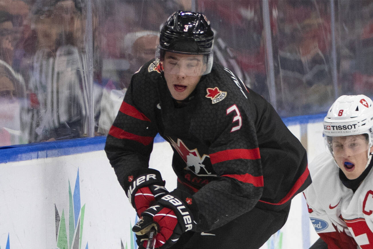 Canada's Olen Zellweger (3) and Switzerland's Simon Knak (8) compete for the puck during the second period in a quarterfinal in the IIHF junior world hockey championships Wednesday, Aug. 17, 2022, in Edmonton, Alberta. (Jason Franson/The Canadian Press via AP)