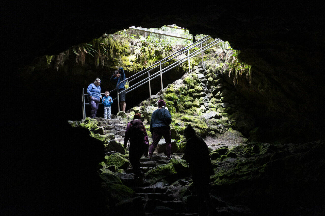 Hikers walk near the entrance of Ape Cave in Gifford Pinchot National Forest. The cave is a series of lava tubes from an eruption of Mount St. Helens 2,000 years ago. (Taylor Balkom / The Columbian)