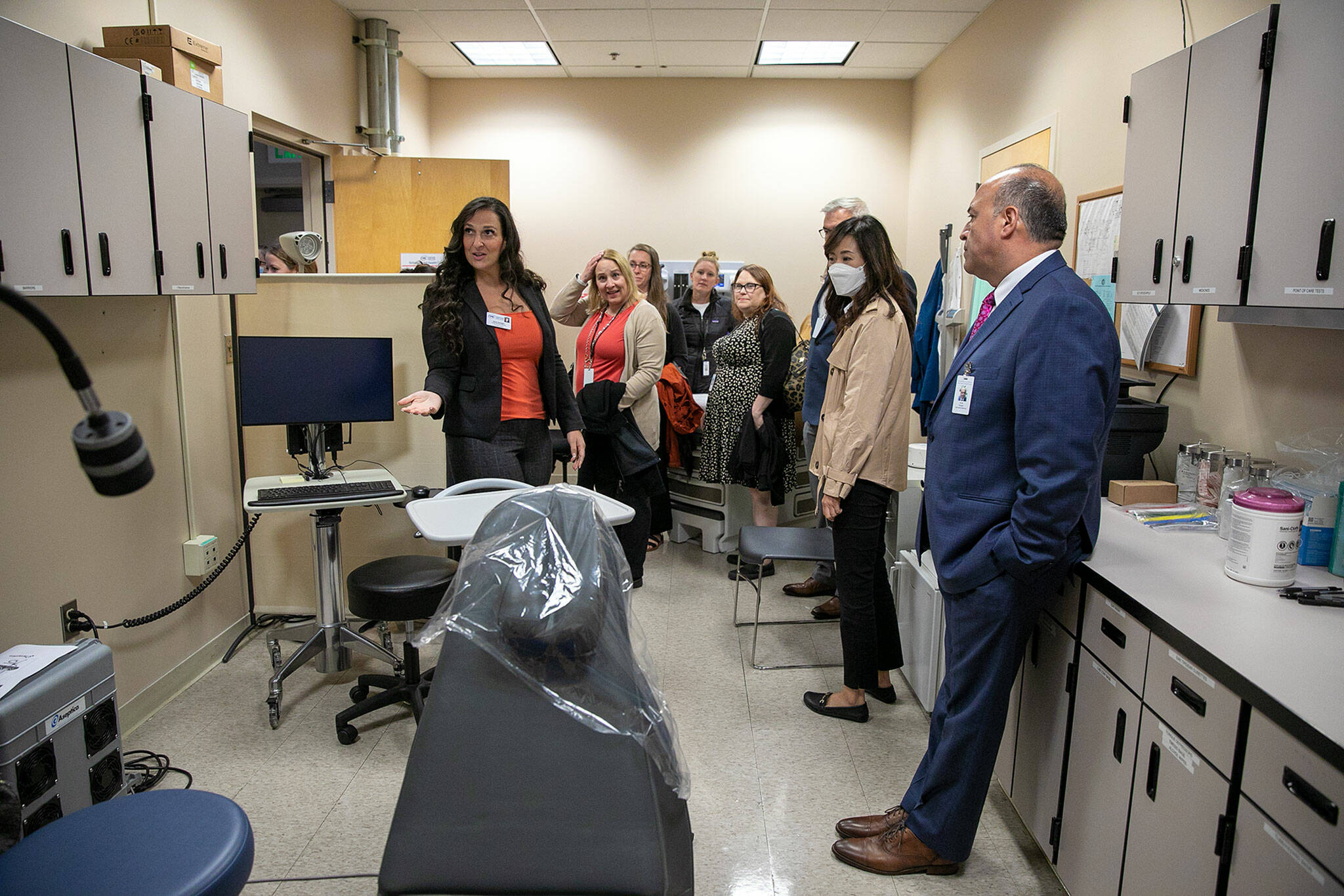 People begin to peruse the temporary space for the new school health center at Meadowdale High School with the help of Community Health Center’s Anna Scheglov, left, on Wednesday, in Lynnwood. (Ryan Berry / The Herald)