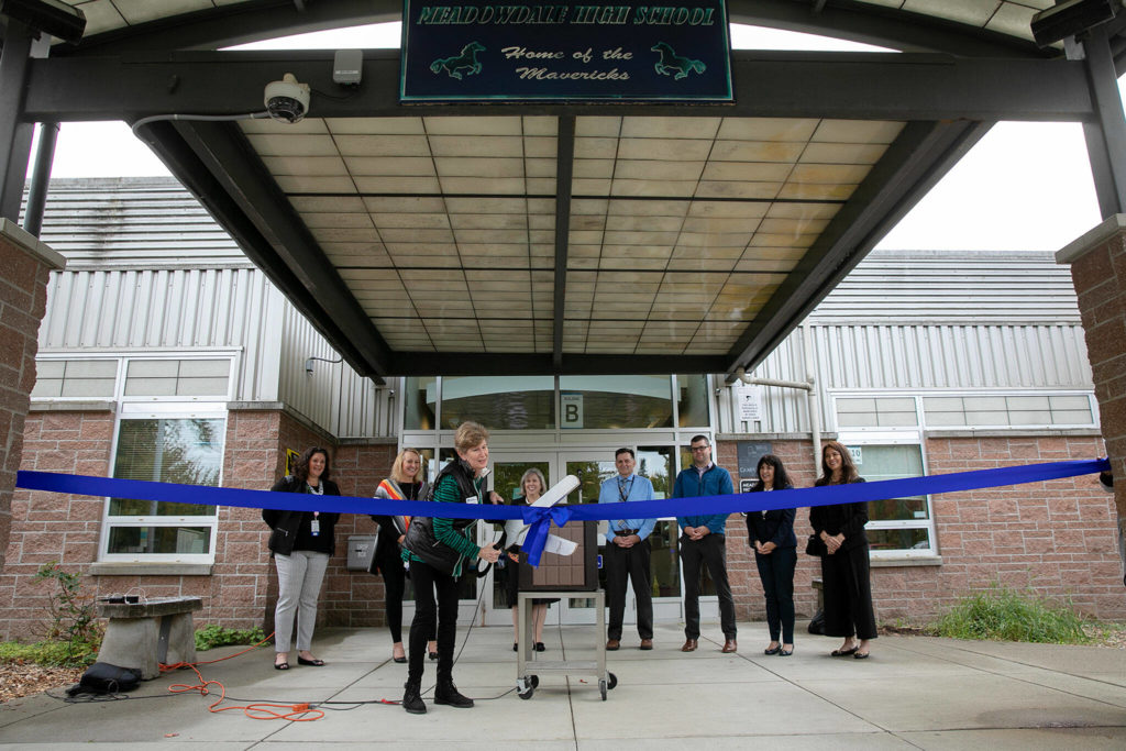 Dr. Nancy Katims, School Board Director of the Edmonds School District, cuts the ribbon during an opening ceremony of a new school health center at Meadowdale High School on Wednesday, in Lynnwood. (Ryan Berry / The Herald)
