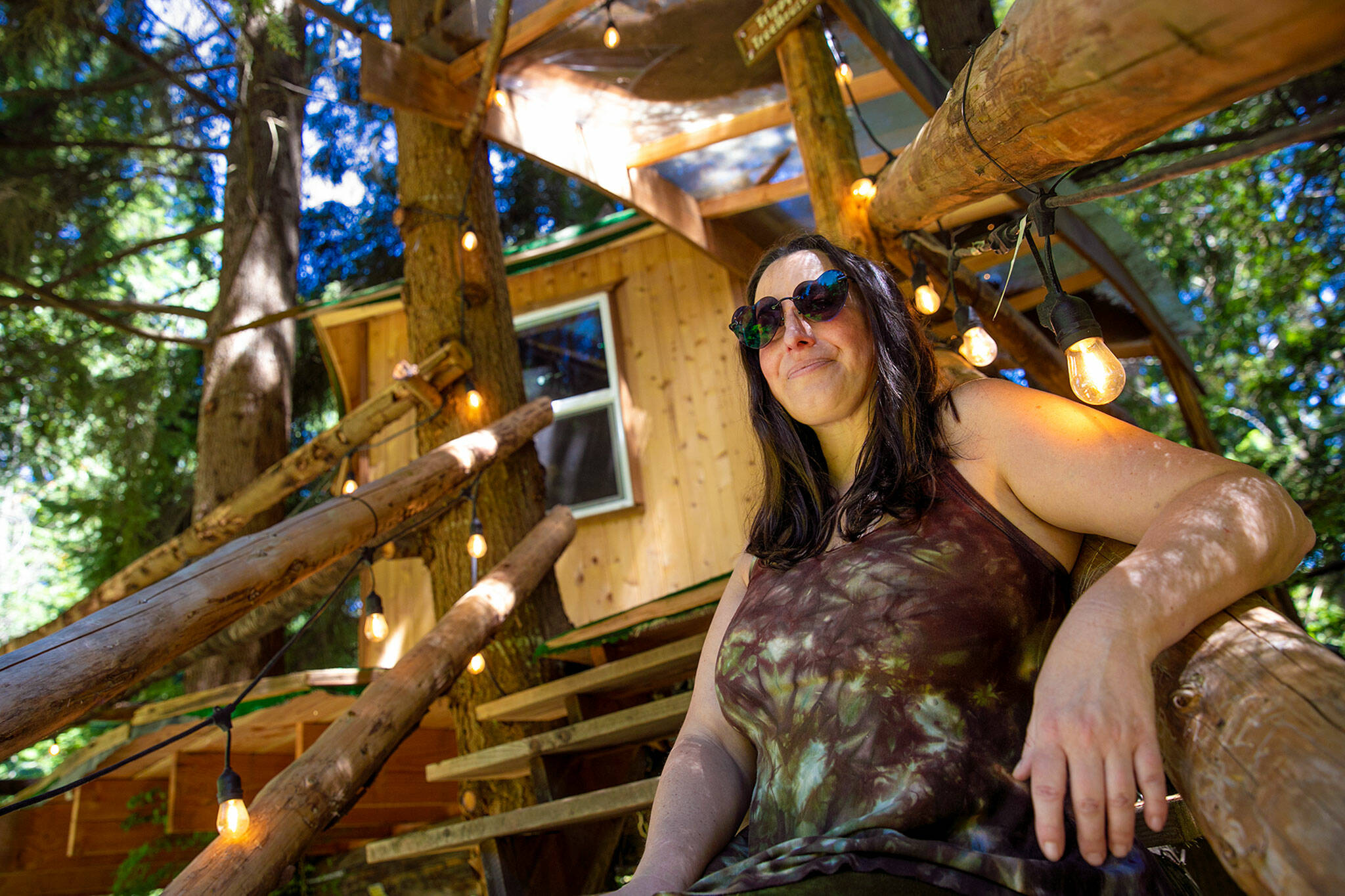 Owner Tracy Rice sits on the steps of the Trippy Treehouse, one of four marijuana-friendly elevated spaces she offers to guests at Mountain Views Tree House BB. (Ryan Berry / The Herald)