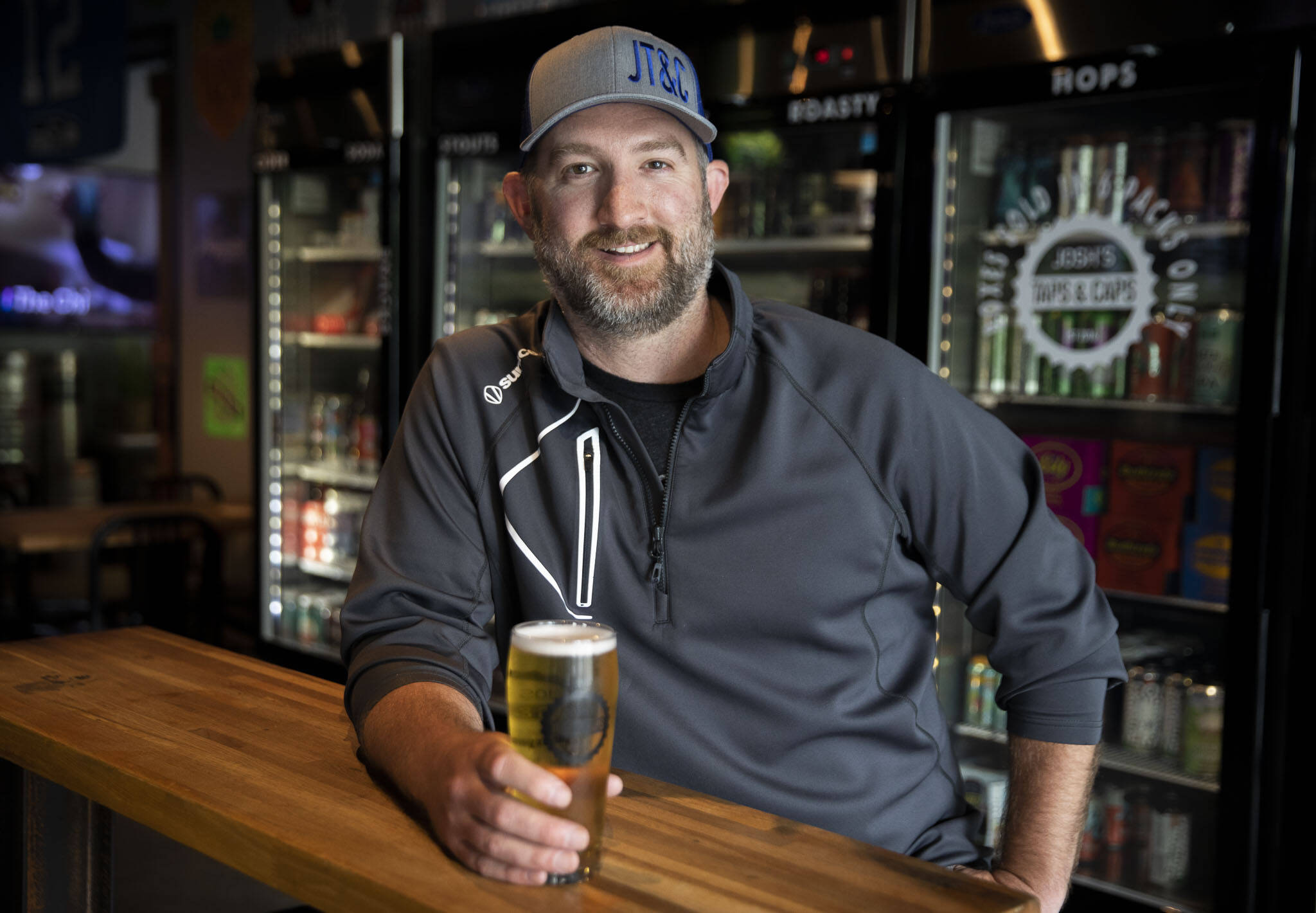 Josh Arnold, owner of Josh’s Taps Caps in Snohomish, relaxes with a glass of his Wayfinder Party Time Pilsner. (Olivia Vanni / The Herald)