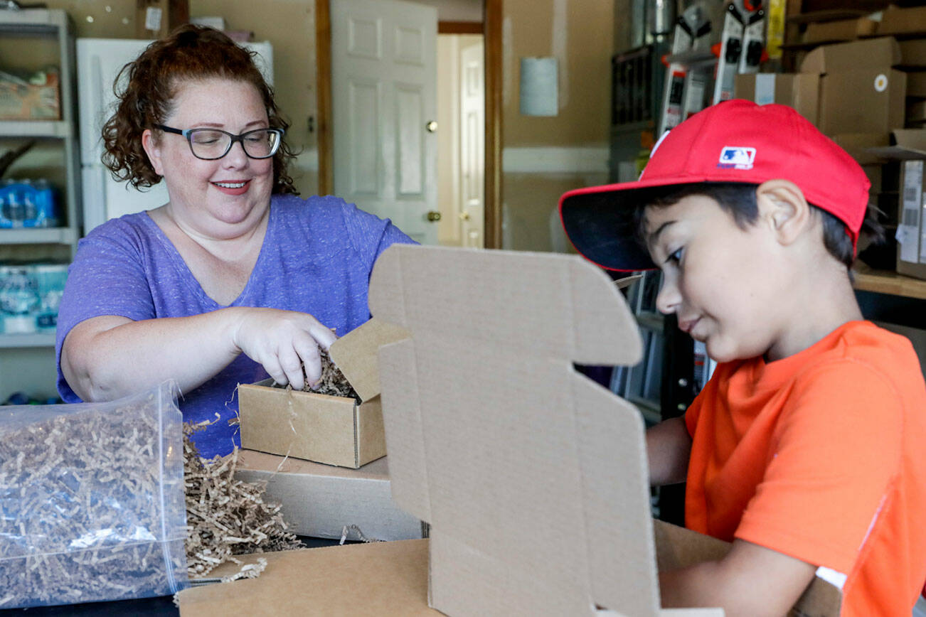 Jenny Piper, left, with her son Jose Piper, 7, assembles disaster preparedness kits at their home in Bothell, Washington on August 11, 2022. (Kevin Clark / The Herald)