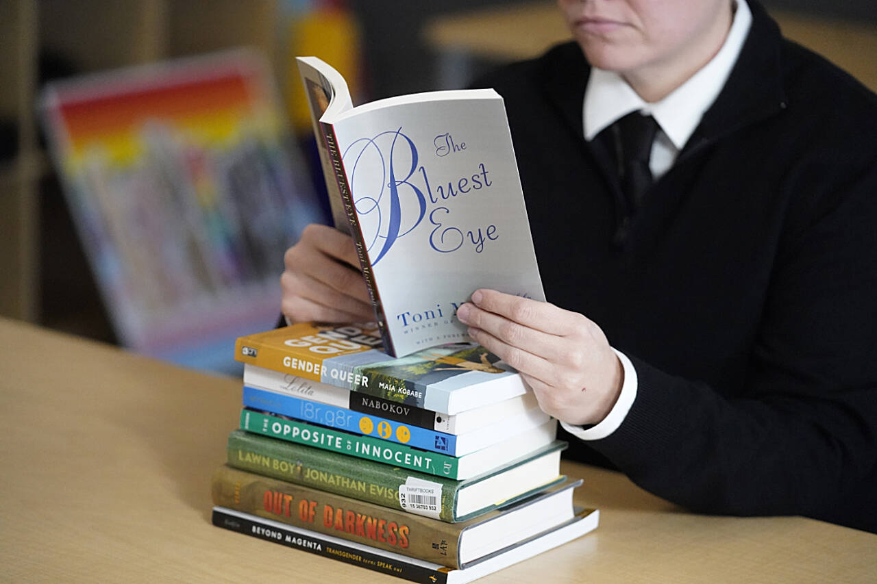 Amanda Darrow, director of youth, family and education programs at the Utah Pride Center, poses with books, including “The Bluest Eye,” by Toni Morrison, that have been the subject of complaints from parents in Salt Lake City, in December, 2021. A wave of book bannings around the country has reached a level not seen for decades. (Rick Bowmer / Associated Press File photo)