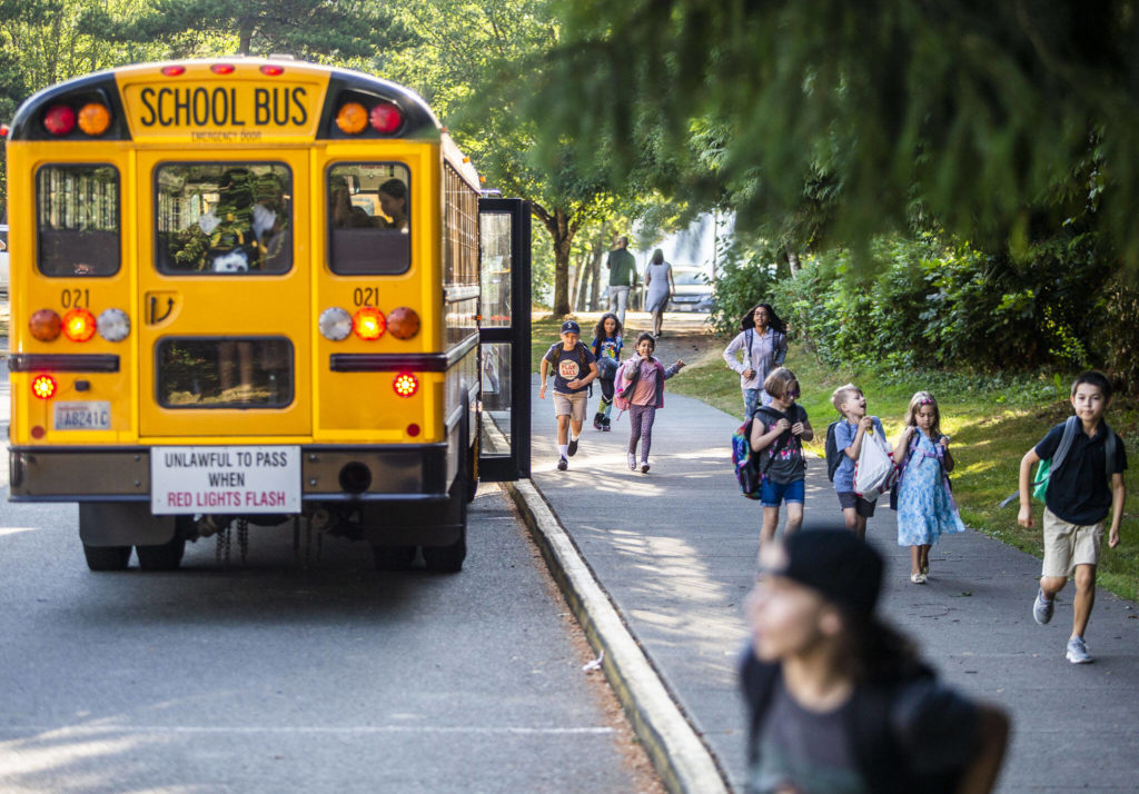 Children get off the school bus at Highland Elementary and run to class during the first day of school on Wednesday, in Lake Stevens. (Olivia Vanni / The Herald) 
