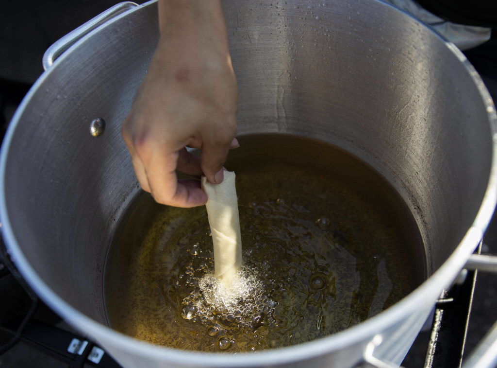 Jessica Aubert places a lumpia into hot oil to fry. (Olivia Vanni / The Herald)
