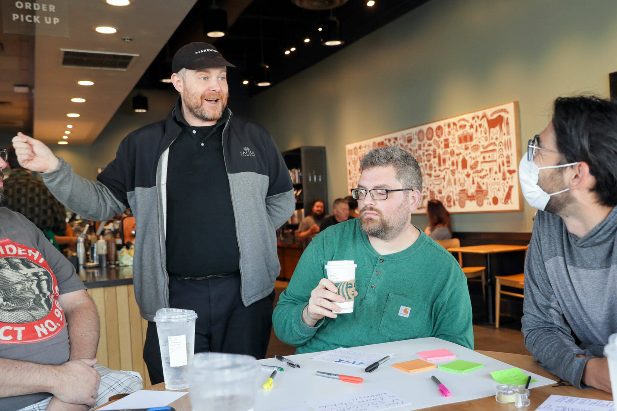 Tom Bosserman, left to right, Cornelius Ersoz and Nick Watkin on Monday morning during a “sip in” at Starbucks for union solidarity in Everett. (Kevin Clark / The Herald)