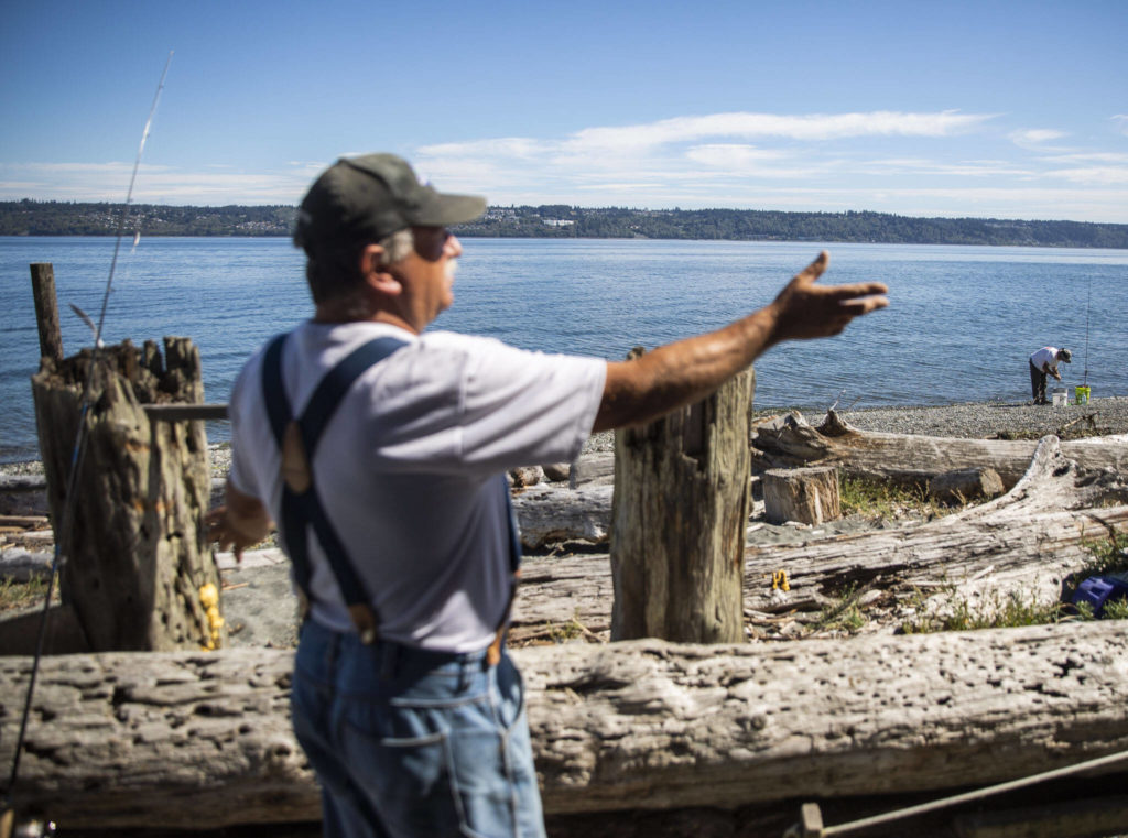 A fisherman puts fresh bait on his hook while Dan Cooper talks about fishing restrictions. (Olivia Vanni / The Herald)
