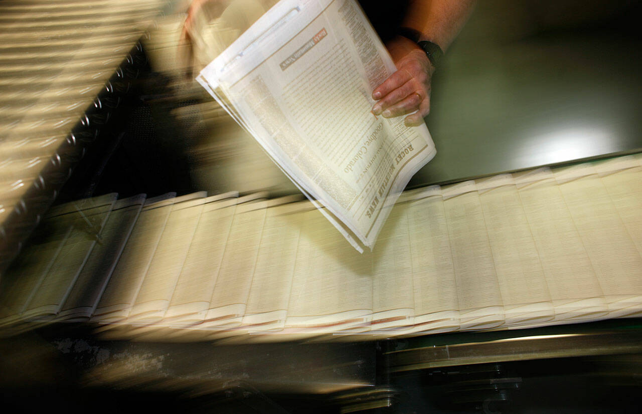 A pressman pulls a copy of one of the final editions of the Rocky Mountain News off a press at the Washington Street Printing Plant of the Denver Newspaper Agency in Denver, on Feb. 26, 2009. (AP Photo/David Zalubowski, File)