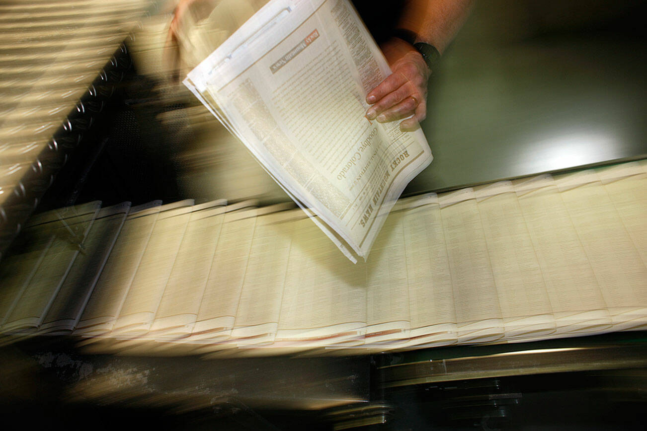 FILE - In this Feb. 26, 2009 file photo, a pressman pulls a copy of one of the final editions of the Rocky Mountain News off the press in the Washington Street Printing Plant of the Denver Newspaper Agency in Denver. A survey by Gallup and the Knight Foundation released on Sunday, Nov. 17, 2019, finds Democrats much more willing than Republicans to see government funding help local news sources. (AP Photo/David Zalubowski, File)