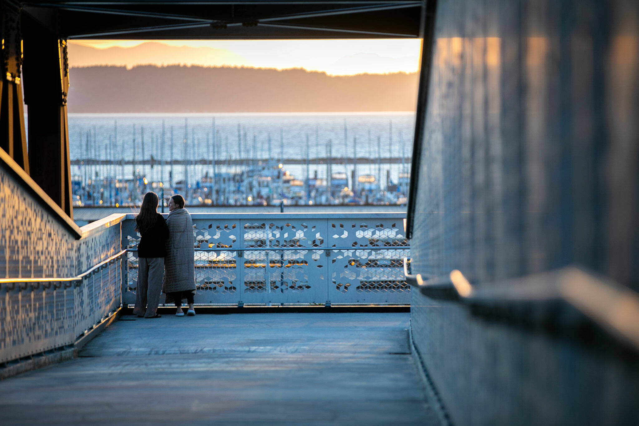 Two people take in the sunset view looking west from the Grand Ave Park Bridge on Wednesday, in Everett. (Ryan Berry / The Herald)