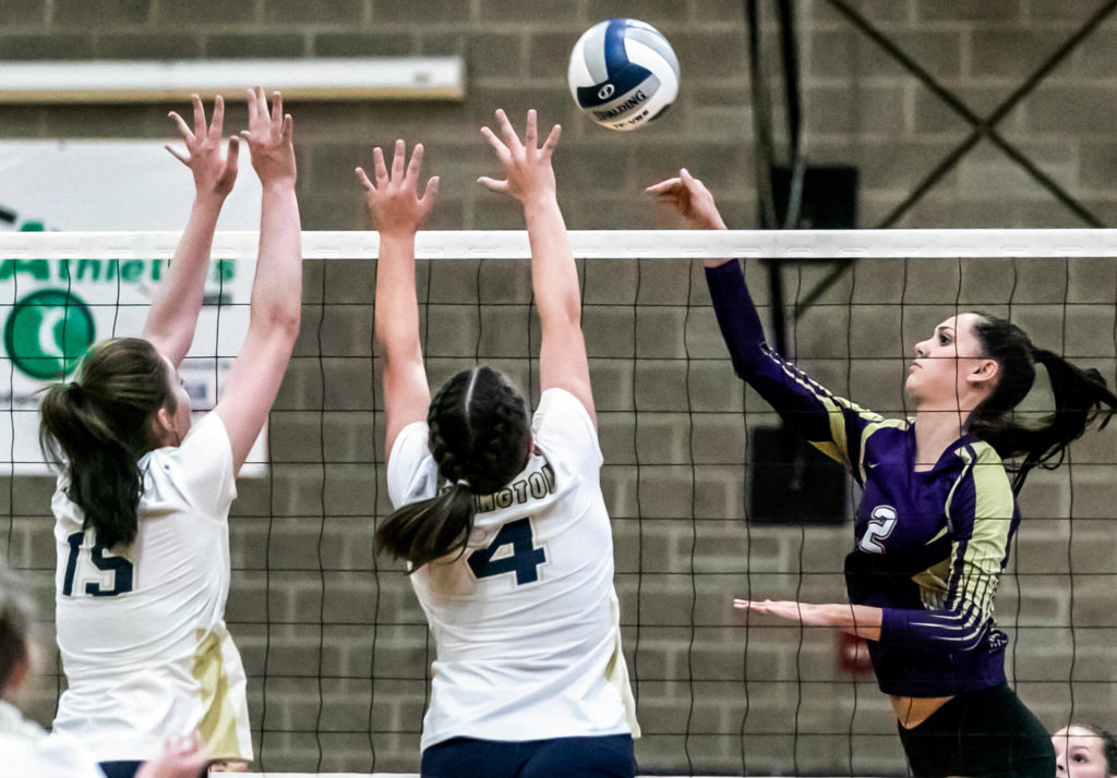 Lake Stevens’ Bella Christensen, right, attempts a kill with Arlington’s Caitlin Klein, left, and Cadynce Knudson blocking Tuesday evening at Arlington High School in Arlington, Washington on September 6, 2022. The Vikings won the straight sets. (Kevin Clark / The Herald)
